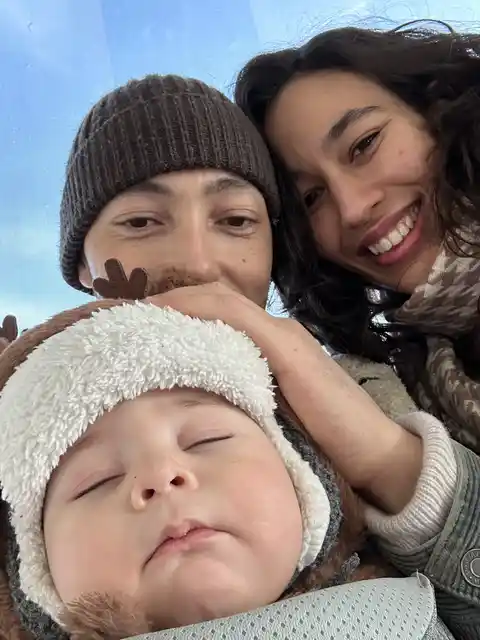 A close family selfie bundled up in warm hats and coats on a cold day.