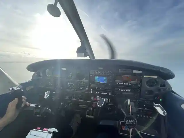A light aircraft cockpit and instrument panel with the propeller and sky ahead.