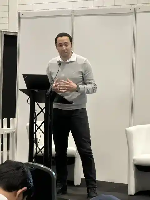 A speaker standing at a lectern with a laptop and microphone.